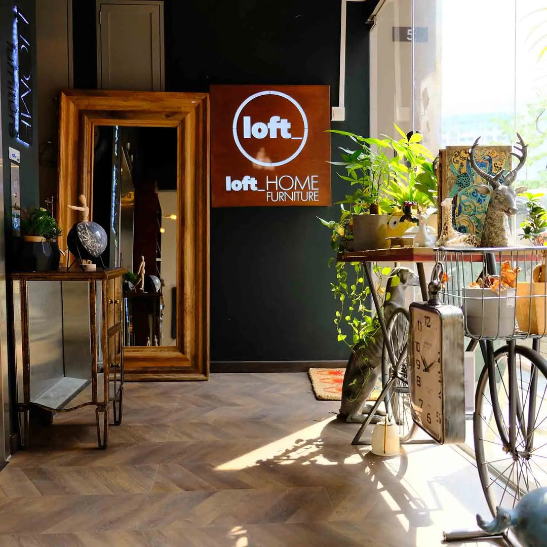 Featured in Loft Home's furniture collection: Entryway of a modern furniture store with stylish decor, large mirror, plants, and a bicycle-themed display.
