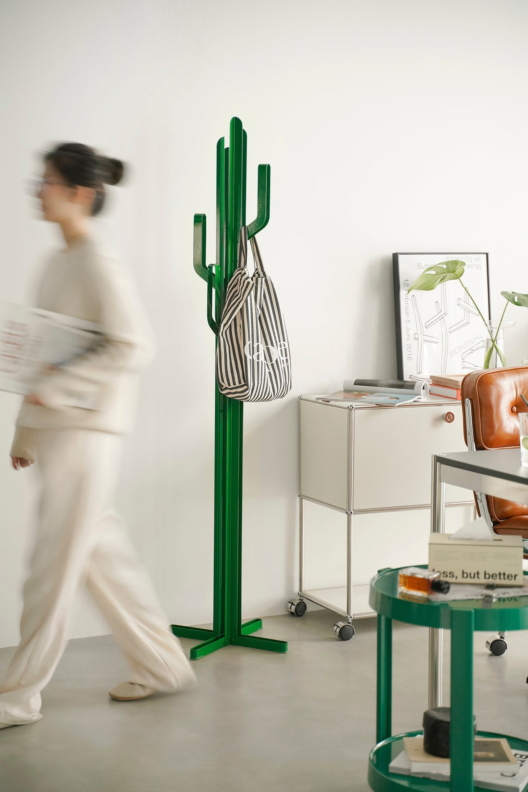 Green cactus-shaped clothes hanger with a striped bag against a white wall. Loft Home clothes hangers collection cover photo.