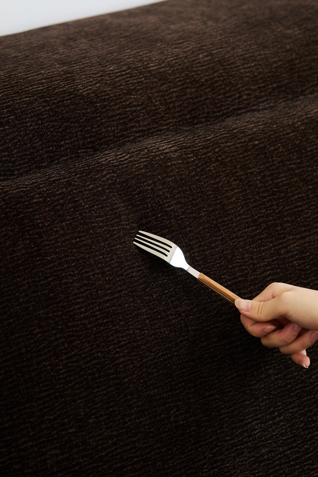 Scratch-resistant brown fabric sofa tested with a fork, designed for durable comfort in modern US homes and apartments.