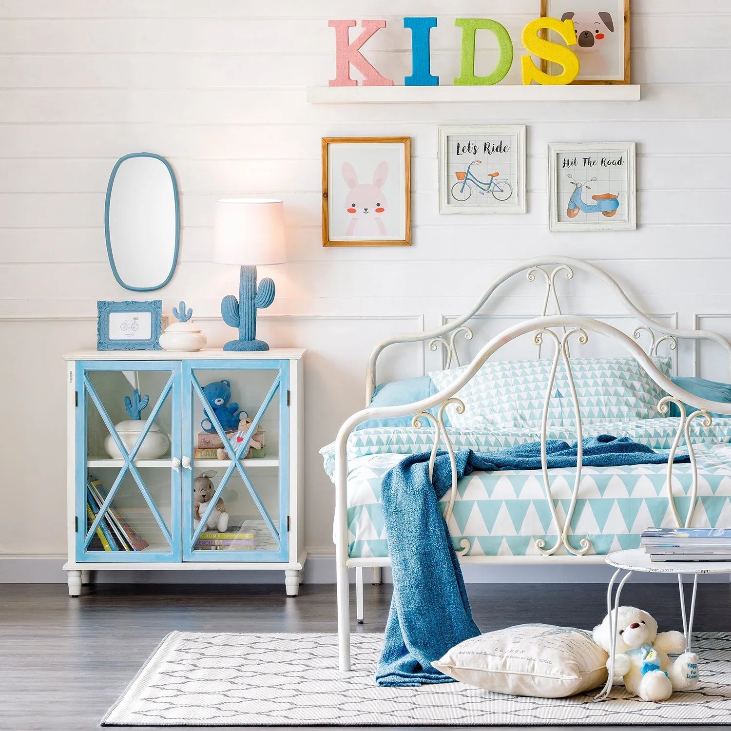 Loft Home kids' room with a white metal bed frame, pastel blue cabinet, and playful wall decor, creating a cozy and colorful space for children.