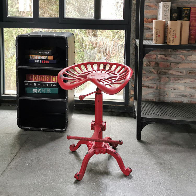 Industrial-style height-adjustable stool with a bold red finish and a vintage tractor seat design, ideal for adding a pop of color to creative spaces.