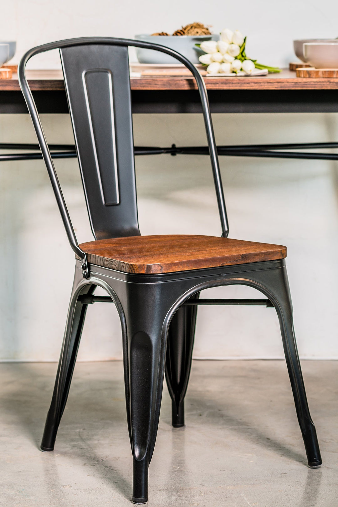 Black metal chair with a wooden seat in a casual dining setting. Featured in Loft Home's metal chairs collection.