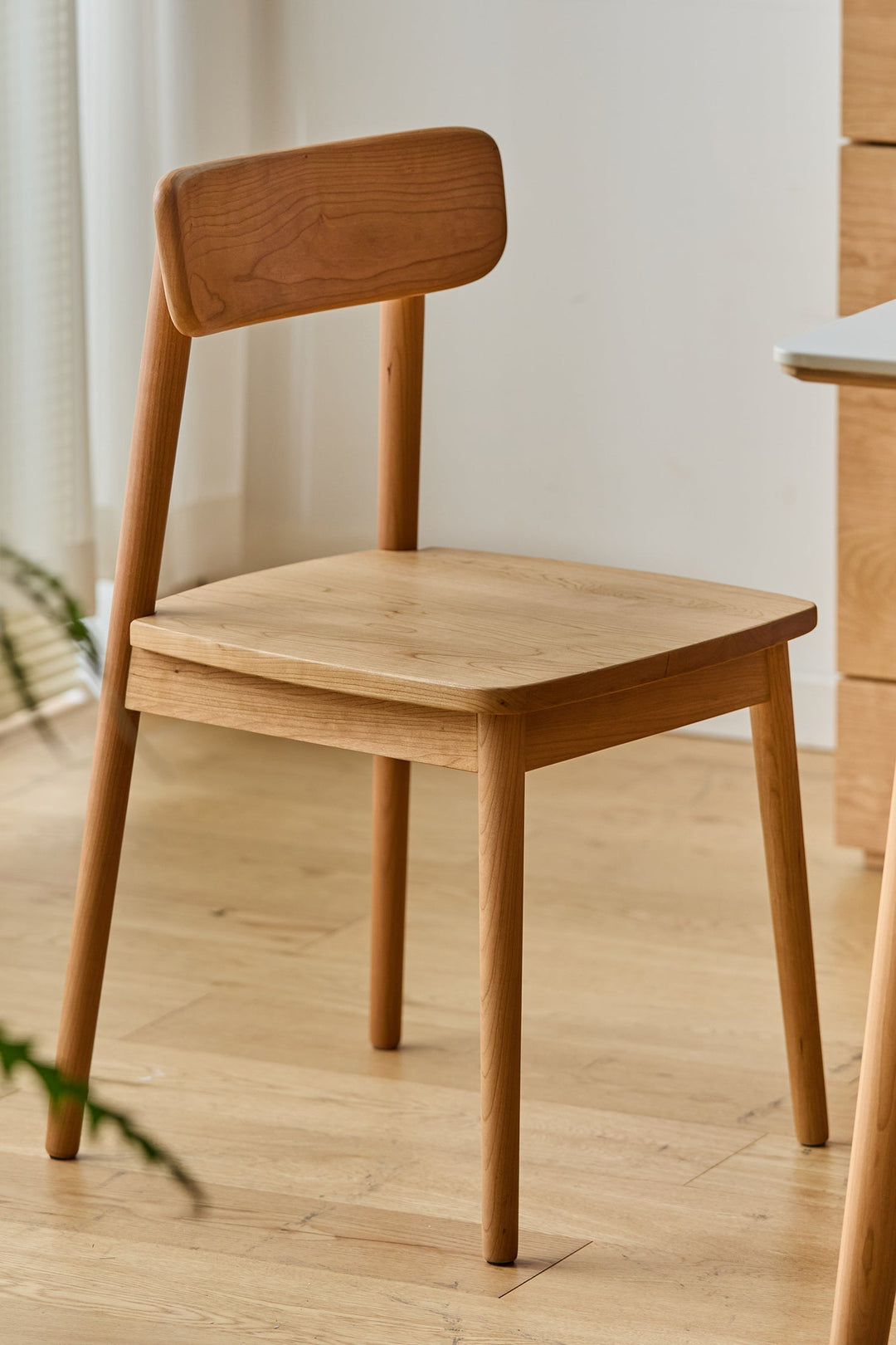 Wooden chair on a wooden floor with a neutral background. Featured in Loft Home Singapore's wooden chairs collection.