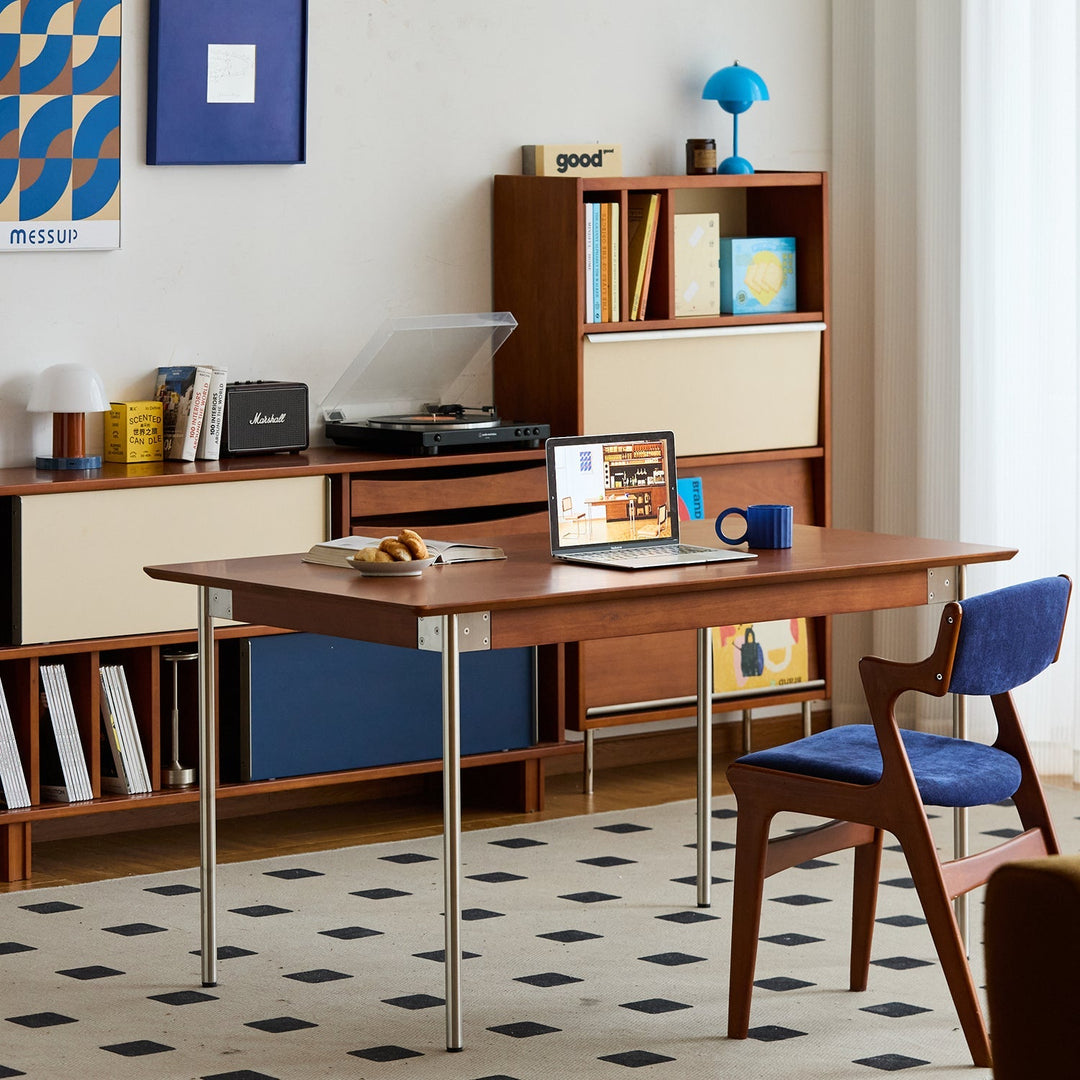 Bauhaus-style wooden desk with clean metal legs, paired with a retro blue fabric chair, set in a stylish workspace with modular storage—celebrating functional design and timeless form.