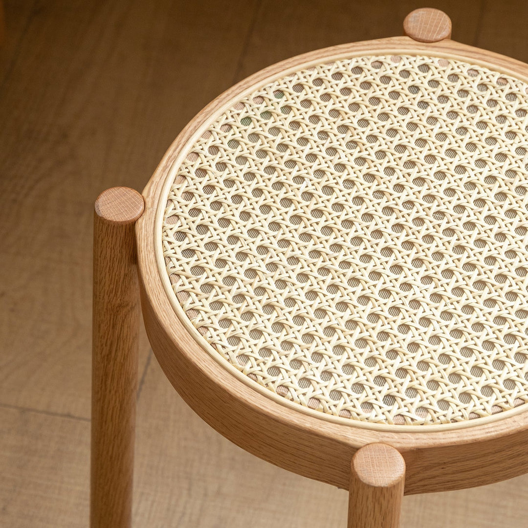 Round rattan stool with a natural woven seat and solid wood frame, combining elegance and durability for stylish seating in any space.