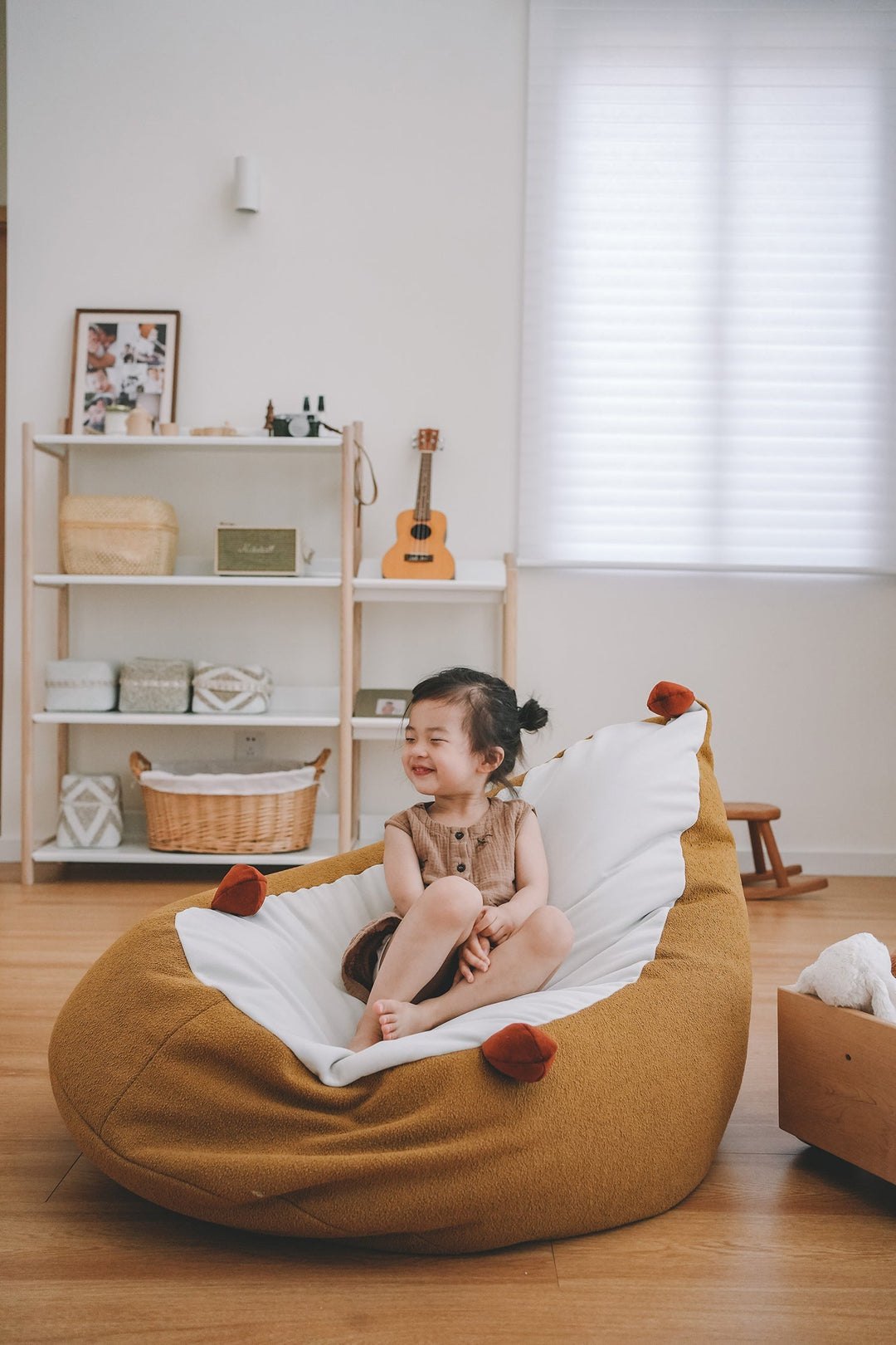 Cozy mustard kids' bean bag in a minimalist Scandinavian room, styled with soft textures and child-friendly decor, creating a playful and warm space.