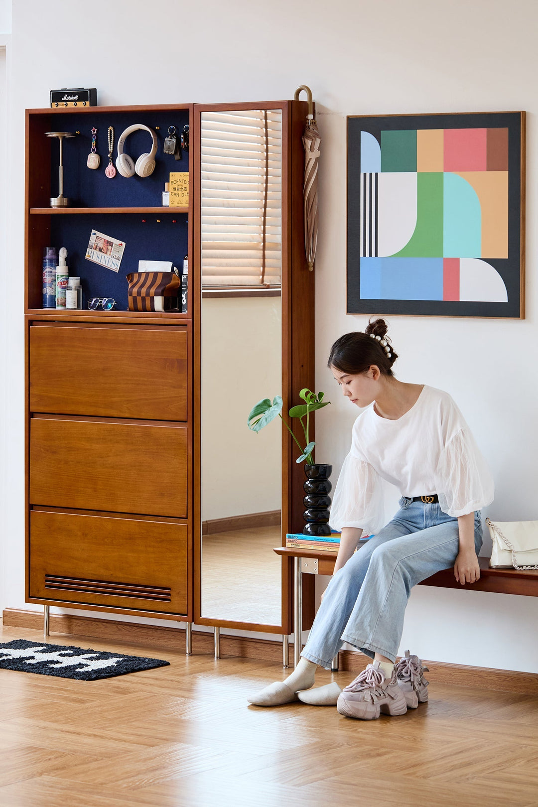 Beside the shoe cabinet, a woman sits on a bench changing her shoes. Loft Home shoe cabinet collection cover photo.