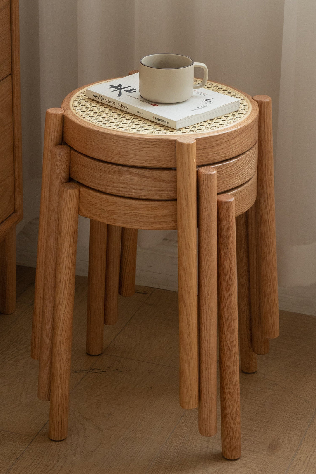 Stackable wooden stools with woven top on a wooden floor. Loft Home stools collection cover picture.