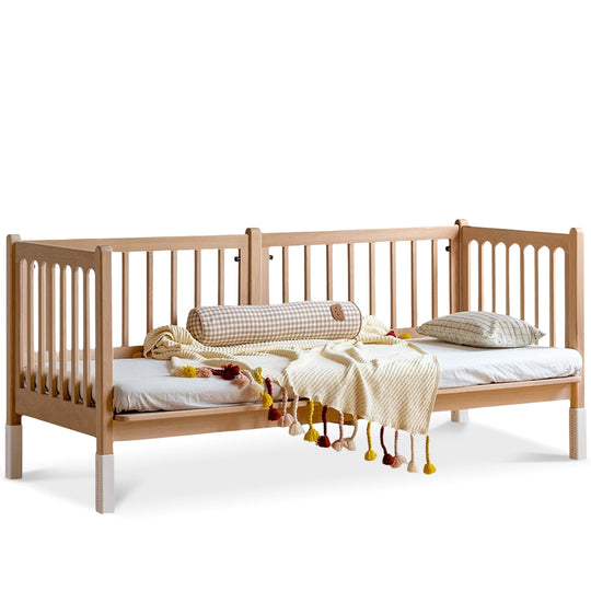 Wooden crib with bedding and toys on a white background