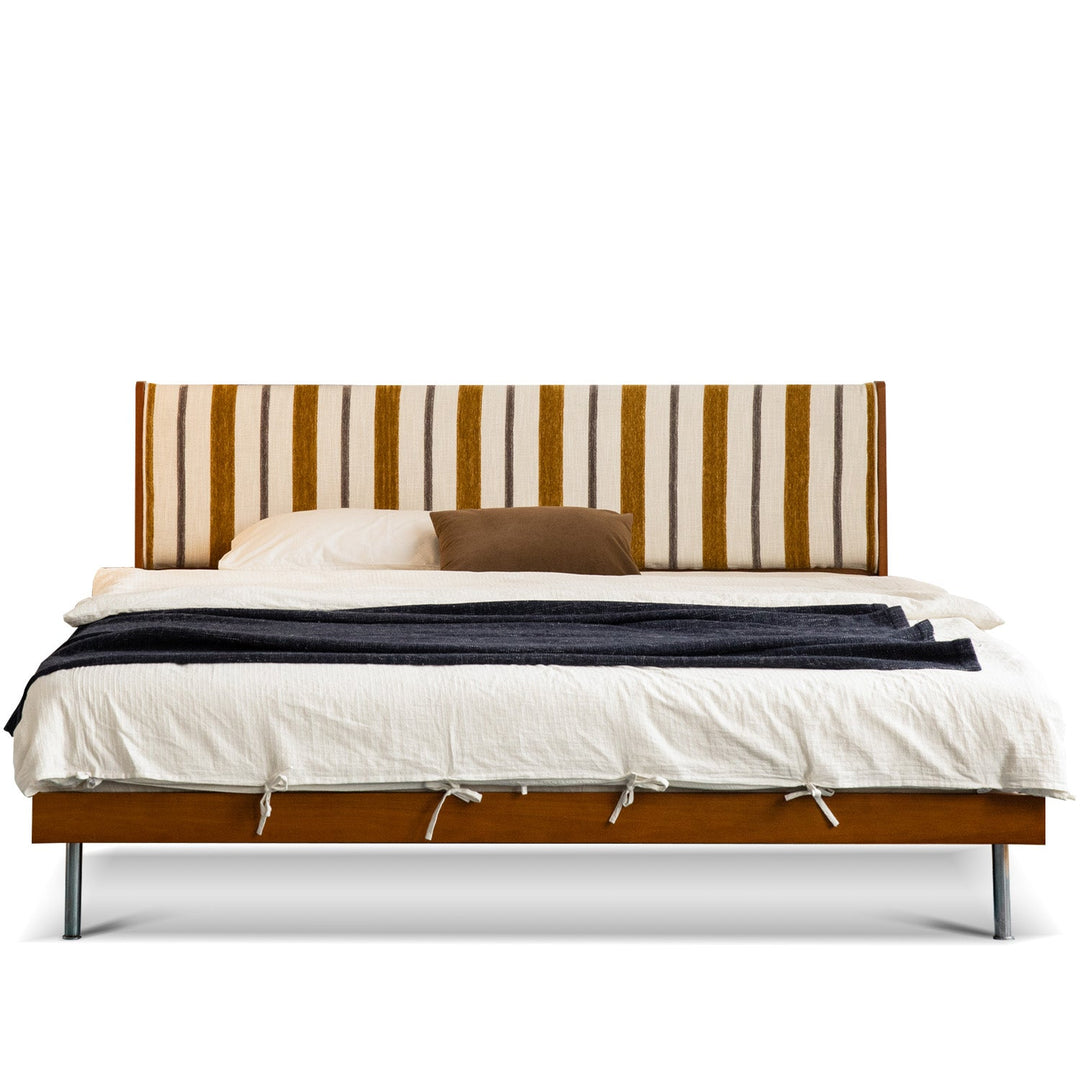 Bed with striped headboard and white bedding on a white background