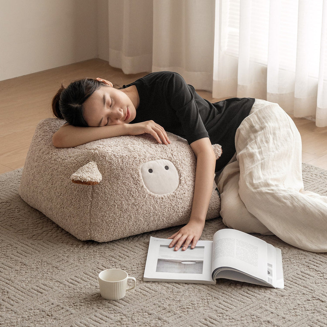 Cream boucle fabric ottoman sheep with context.