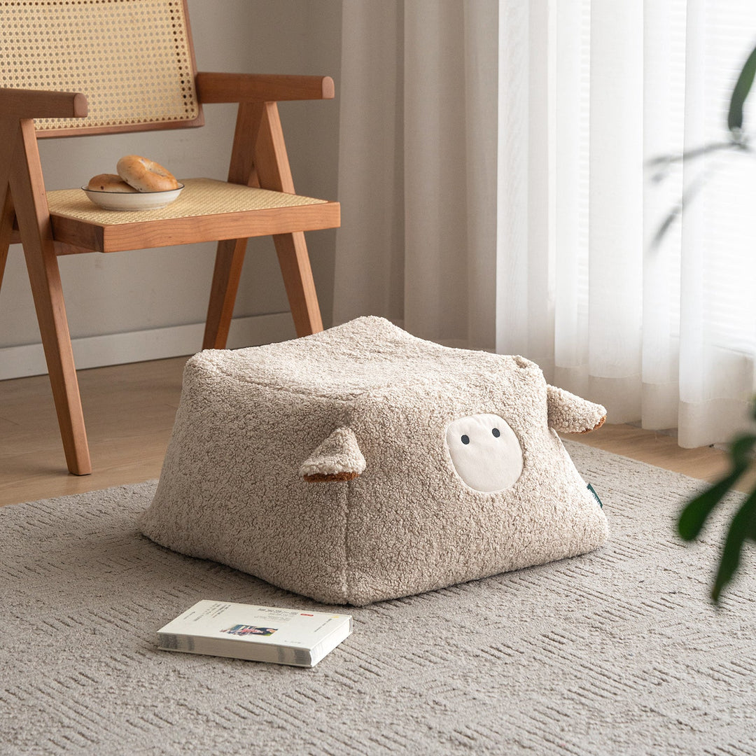 Cream boucle fabric ottoman sheep in close up details.
