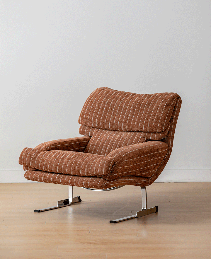 Brown striped upholstered lounge chair with a padded back and seat on chrome sled legs.