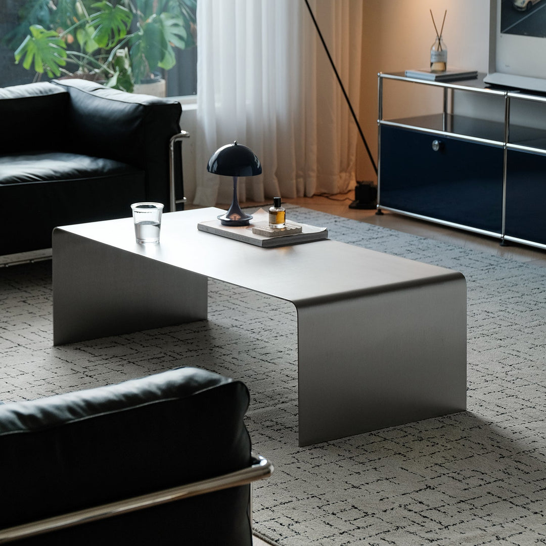 Minimalist steel coffee table arc with context.