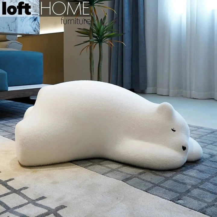 Contemporary velvet ottoman resting bear white in panoramic view.